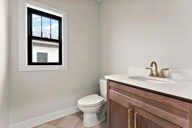 a bathroom with a toilet sink vanity and window