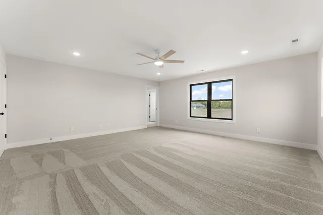 an empty room with windows and ceiling fan