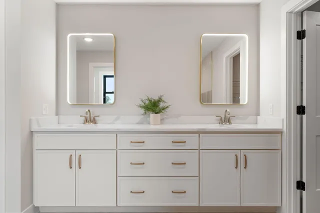 a bathroom with white cabinets sink and mirror