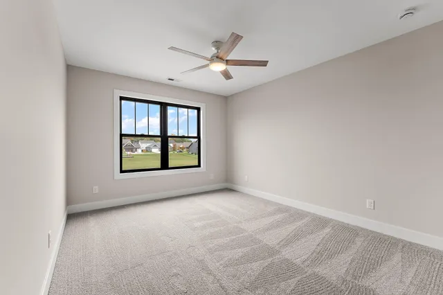 an empty room with windows and ceiling fan