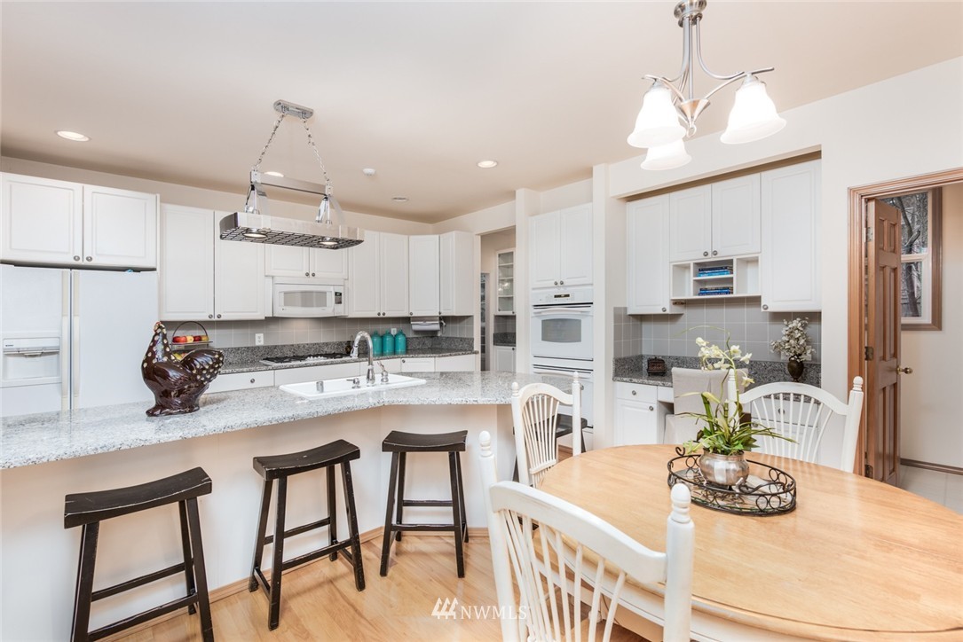 14419 152nd Place Southeast Renton, WA 98059 - Photo 11 of 25 a kitchen with stainless steel appliances kitchen island granite countertop a dining table chairs and white cabinets