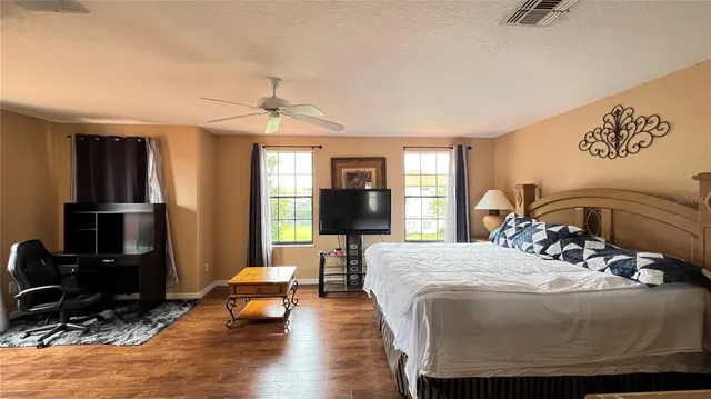 a bedroom with a bed wooden floor and a flat screen tv