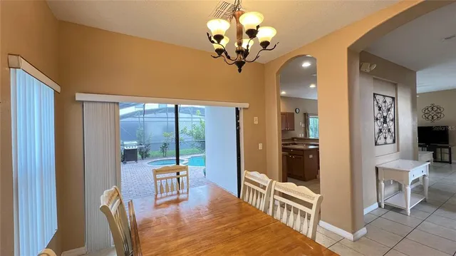 a view of a dining room with furniture a chandelier and large windows