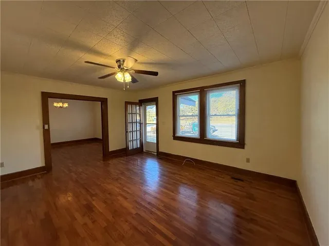 a view of an empty room with window and wooden floor