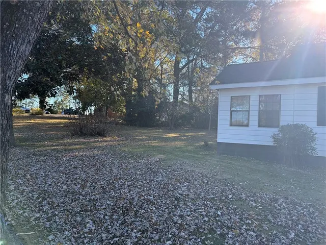 a view of a house with backyard and trees