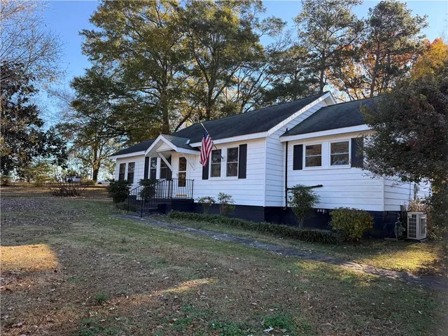 a front view of a house with a garden and trees