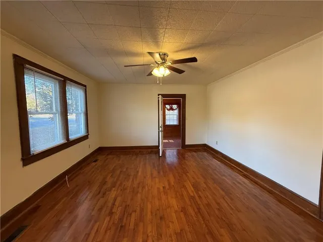a view of an empty room with window and wooden floor