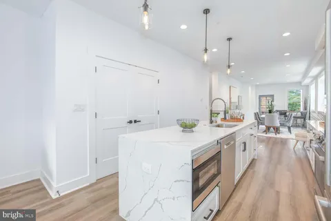 a large white kitchen with a large window a sink and stainless steel appliances