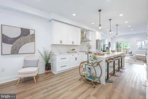 a kitchen with granite countertop white cabinets stainless steel appliances and chairs