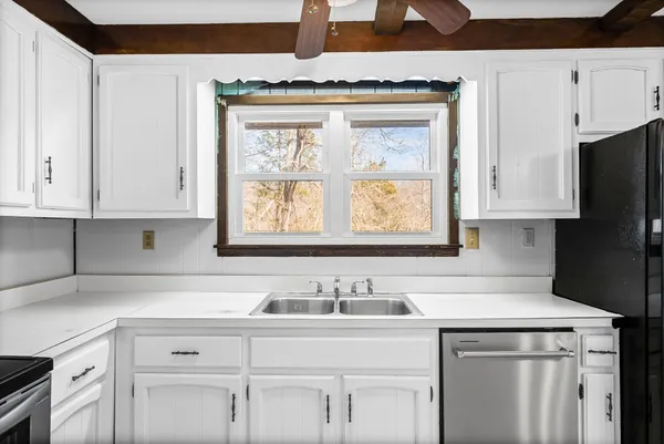 a kitchen with stainless steel appliances granite countertop a sink a stove and white cabinets