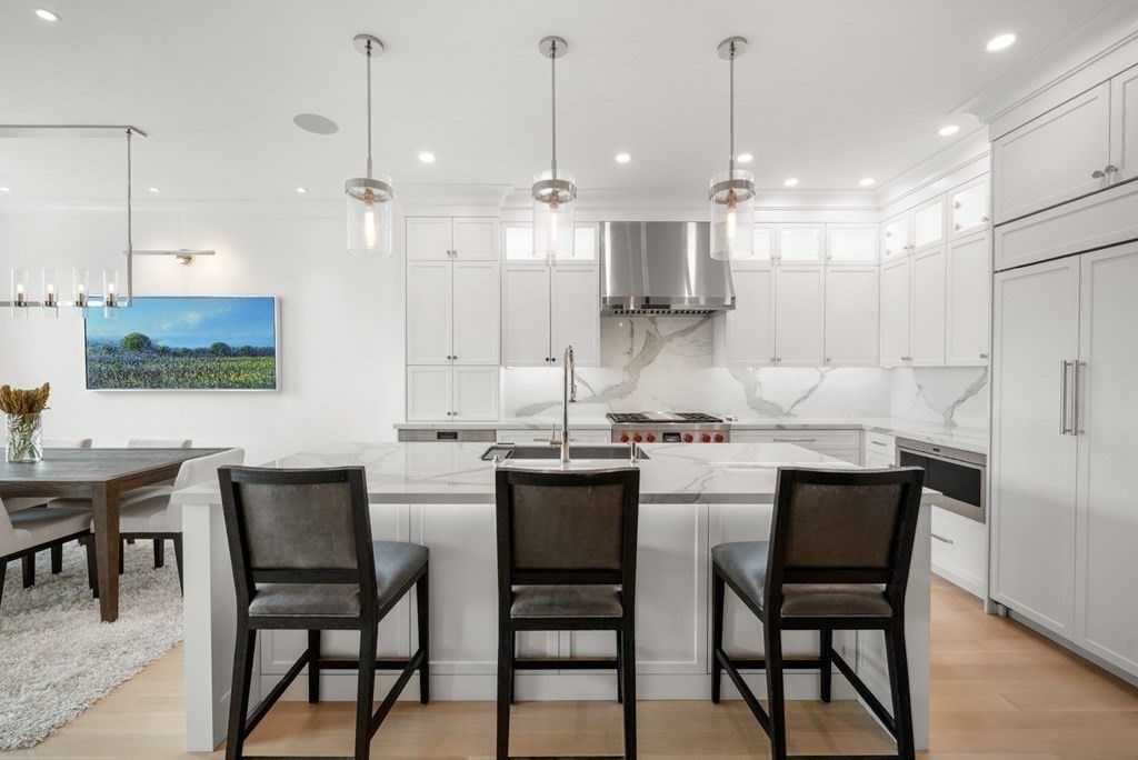 94 Beacon Street, Unit 4 Boston, MA 02108 - Photo 11 of 35 a kitchen with kitchen island a dining table chairs and white cabinets