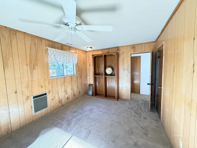 a view of an empty room with chandelier fan and fire place