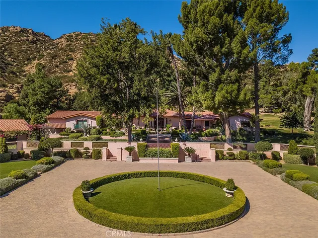 a view of a swimming pool with a yard and large trees