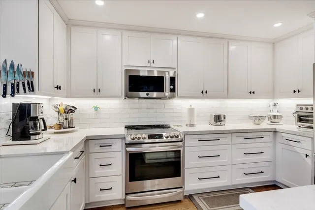 a kitchen with granite countertop white cabinets and stainless steel appliances