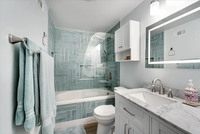 a bathroom with a granite countertop sink toilet and shower
