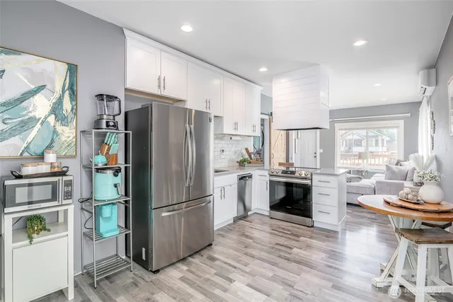 a kitchen with a refrigerator a stove top oven and a dining table with wooden floor