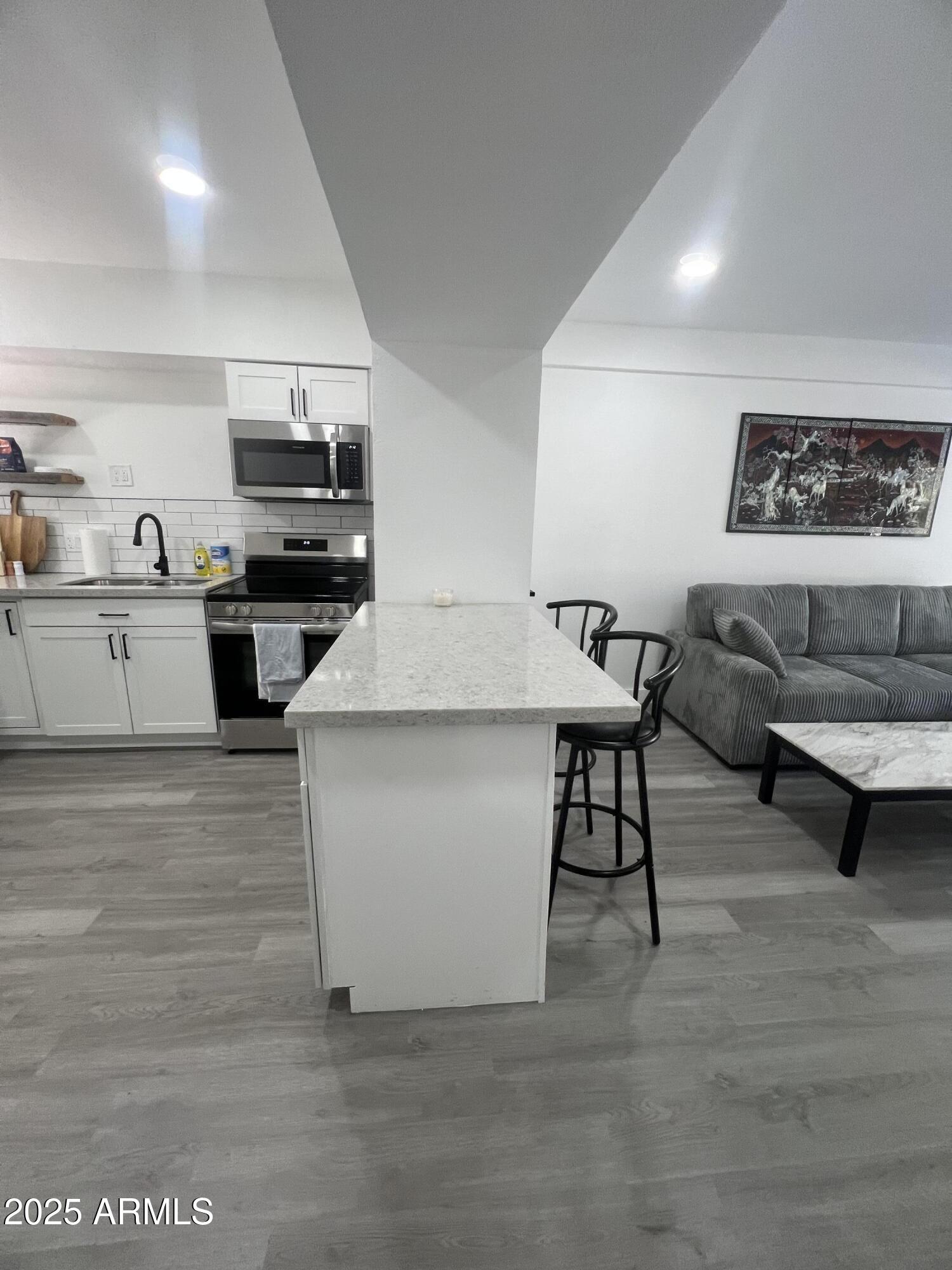 353 East Thomas Road, Unit C104 Phoenix, AZ 85012 - Photo 6 of 17 a living room with stainless steel appliances kitchen island granite countertop furniture and a kitchen view