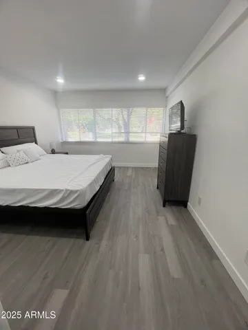 a spacious bedroom with a bed and wooden floor