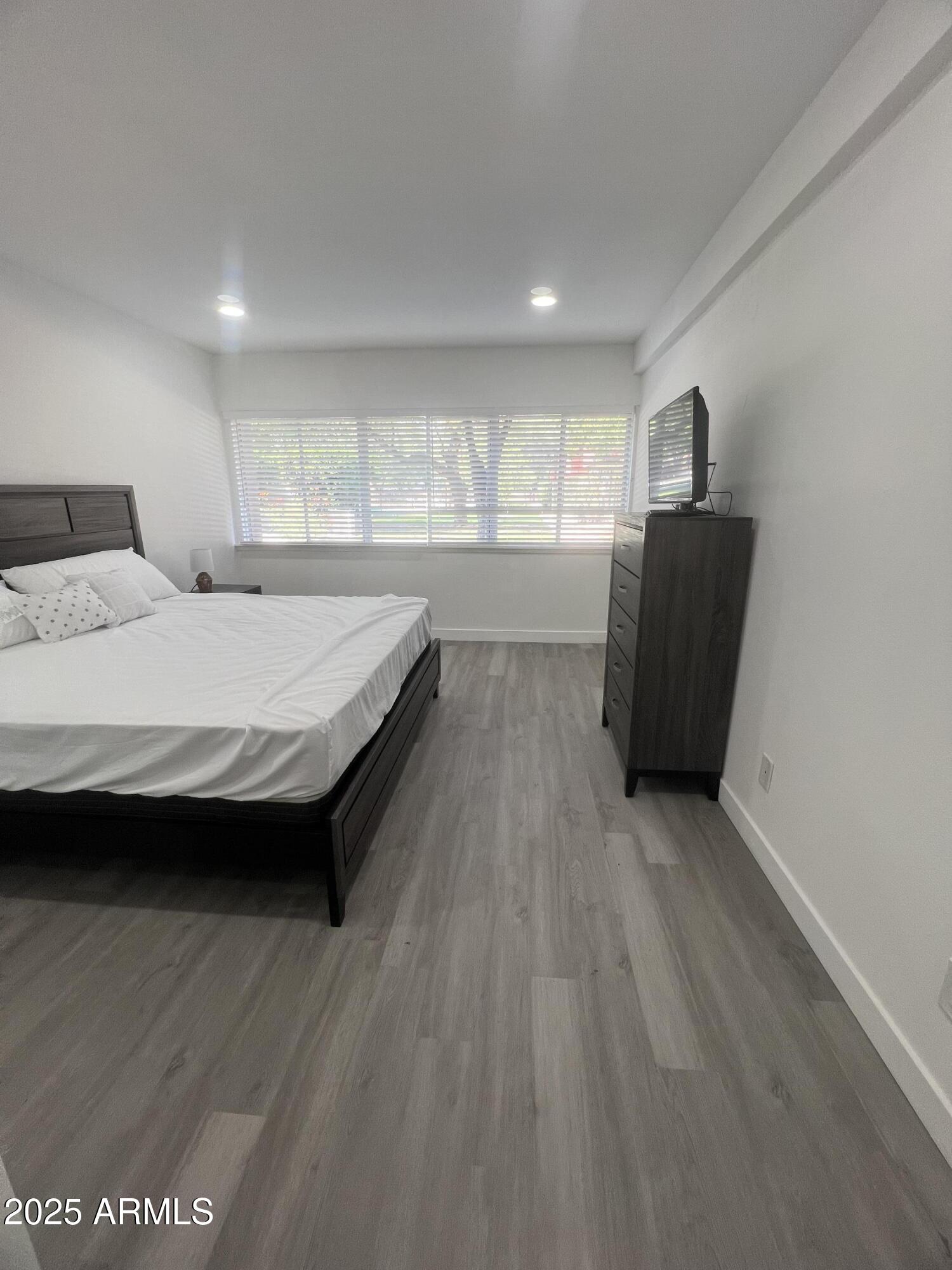 353 East Thomas Road, Unit C104 Phoenix, AZ 85012 - Photo 10 of 17 a spacious bedroom with a bed and wooden floor