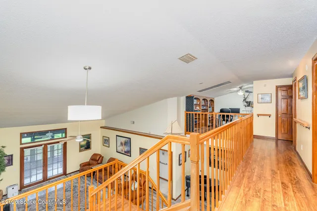 a view of staircase with lots of frames on wall and wooden floor