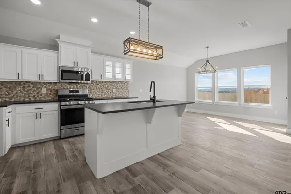 a kitchen with stainless steel appliances granite countertop a stove a sink and a microwave