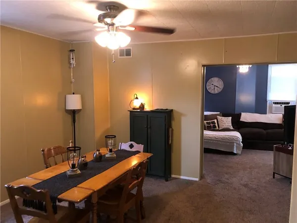 a dining room with furniture and a chandelier fan