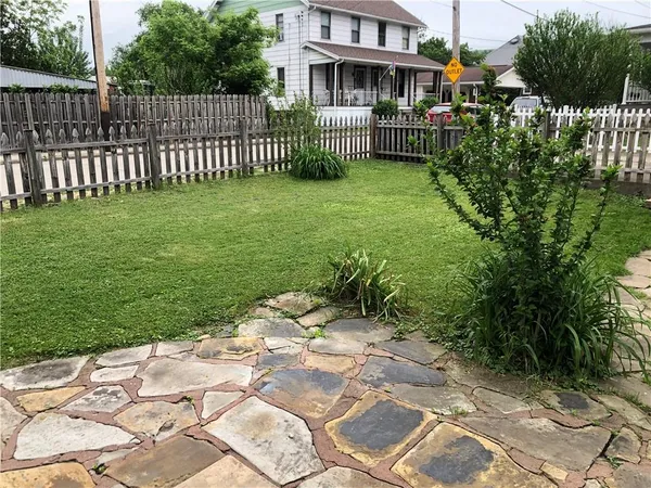 a view of a house with a small yard and wooden fence