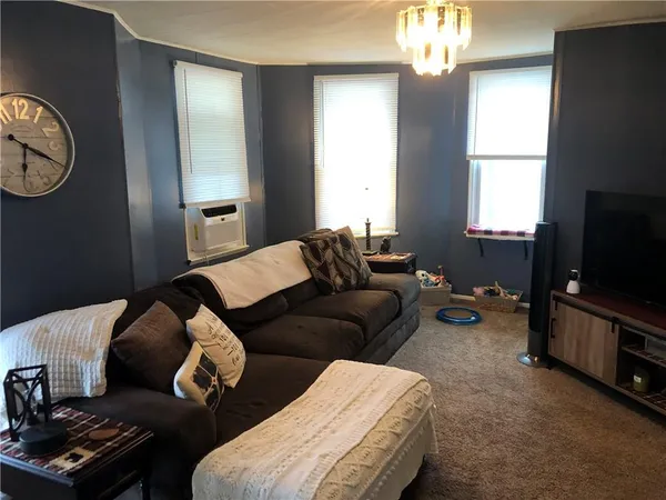 a living room with furniture a chandelier and a window