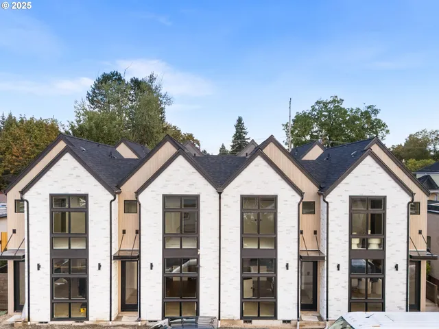a view of a white house with a small yard and large trees