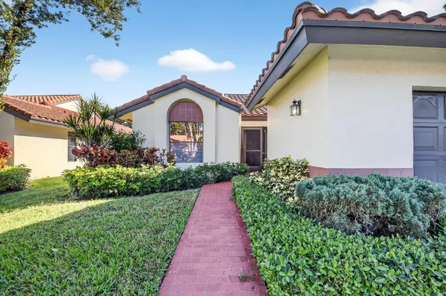 a front view of a house with a yard and potted plants