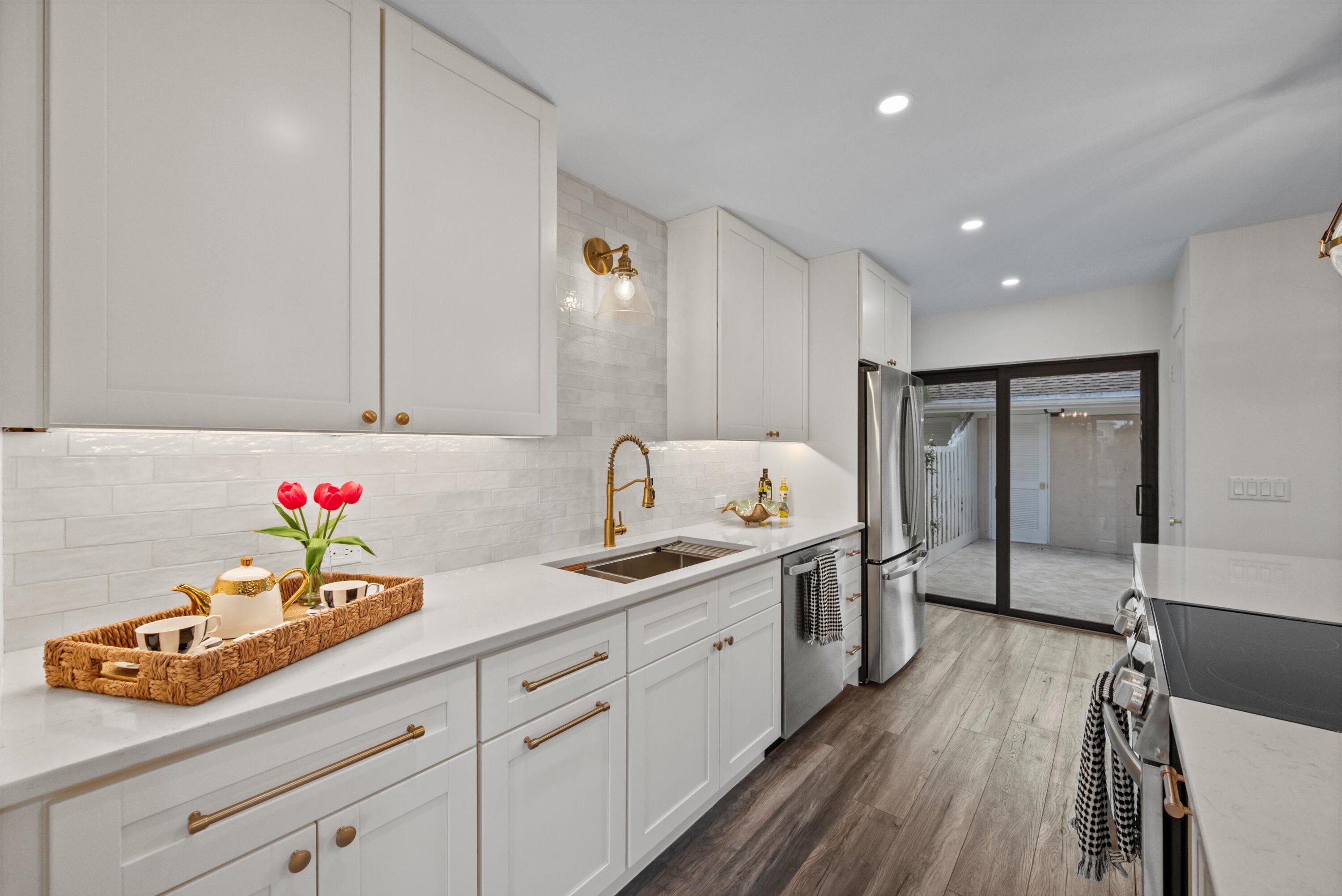 3733 Cape Pointe Circle Jupiter, FL 33477 - Photo 12 of 63 a hallway view with white cabinets stainless steel appliances and wooden floor