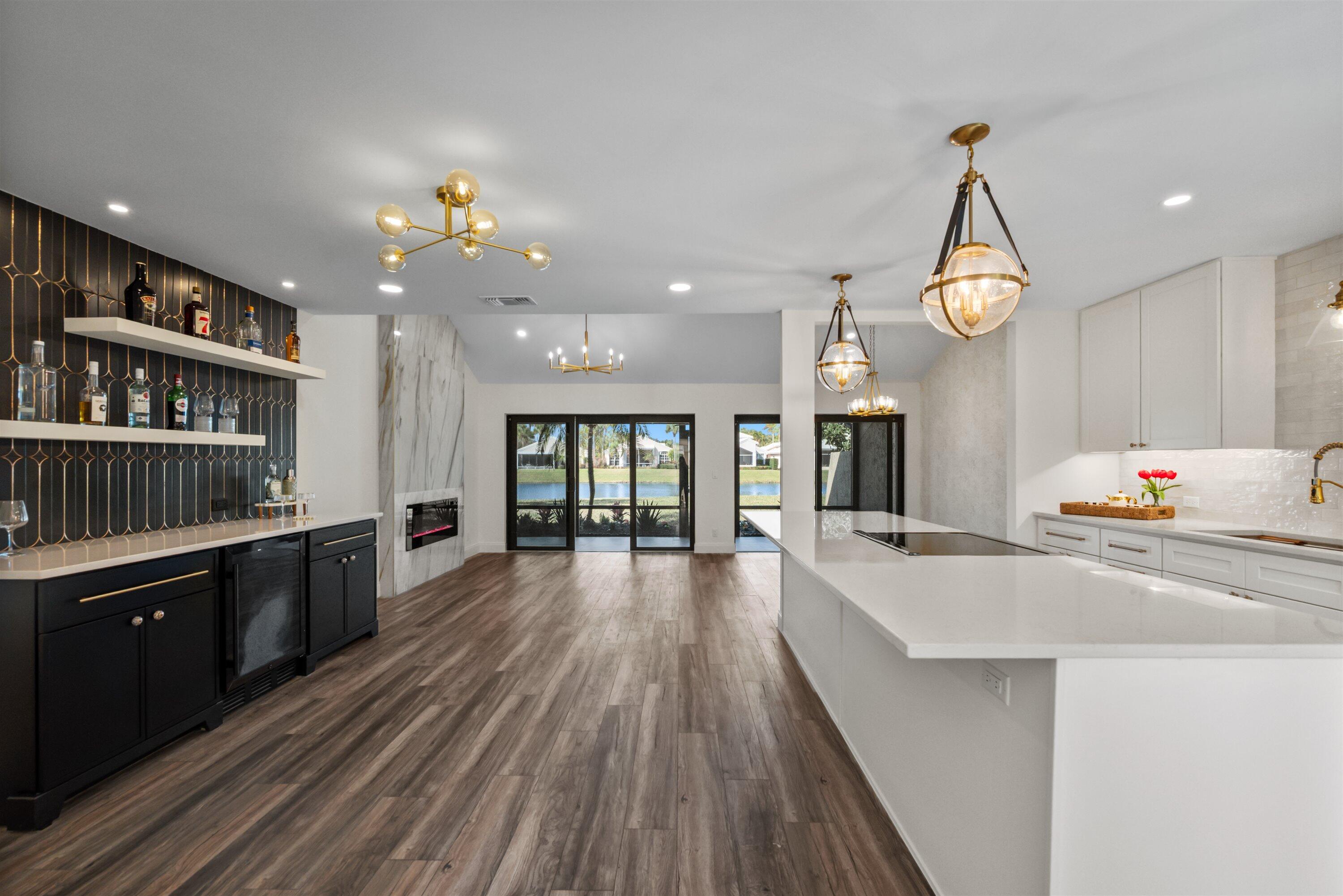 3733 Cape Pointe Circle Jupiter, FL 33477 - Photo 45 of 63 a large kitchen with kitchen island a stove a sink dishwasher and a dining table with wooden floor