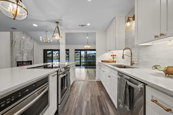 a hallway view with white cabinets stainless steel appliances and wooden floor