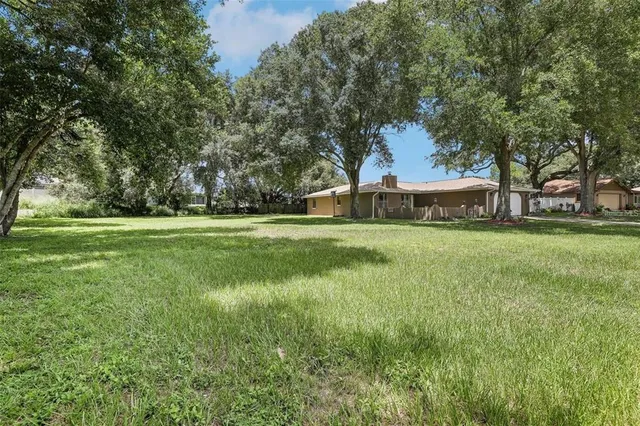 a view of a house with a big yard and large trees