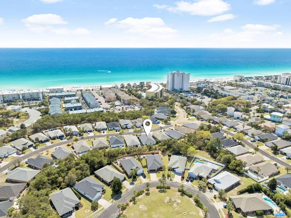 an aerial view of a city with lots of residential buildings and ocean view in back