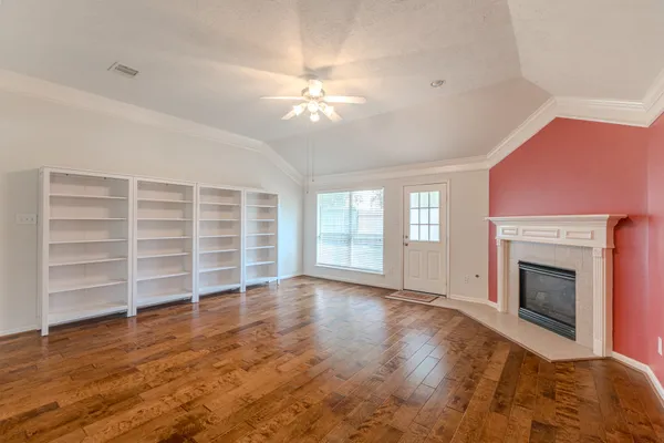 an empty room with chandelier fan and windows