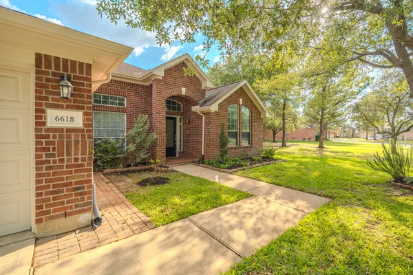 a view of a house with a big yard and large trees
