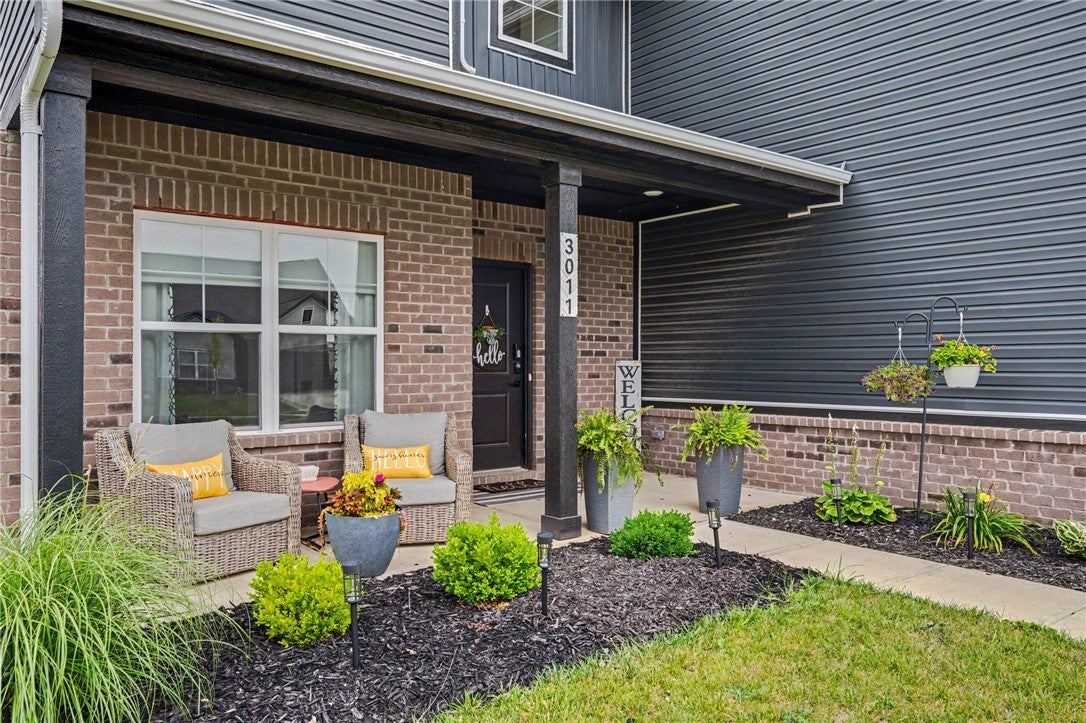 A welcoming brick and siding facade with a covered porch and vibrant landscaping.