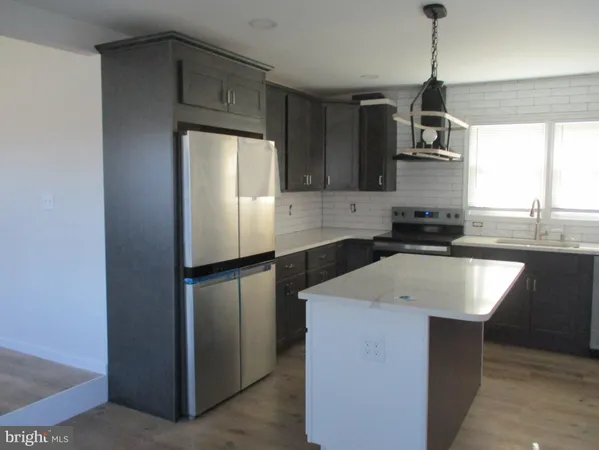 a kitchen with kitchen island granite countertop a sink a counter top space stainless steel appliances and cabinets