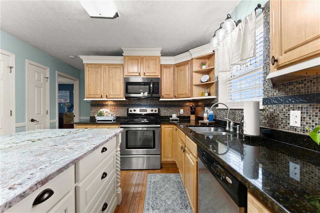 8958 Bill Savage Road Lula, GA 30554 - Photo 19 of 81 a kitchen with stainless steel appliances granite countertop a sink a stove and a microwave
