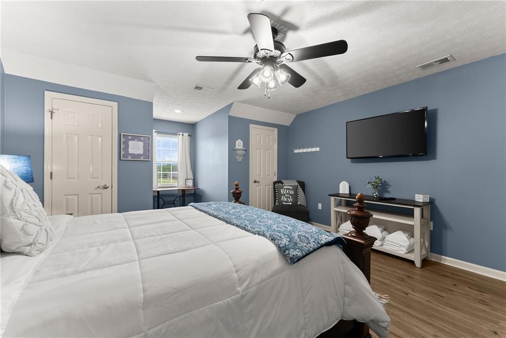 8958 Bill Savage Road Lula, GA 30554 - Photo 38 of 81 a bedroom with a bed and a flat screen tv with wooden floor