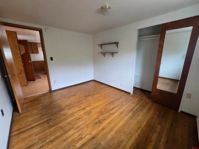 an empty room with wooden floor and mirror