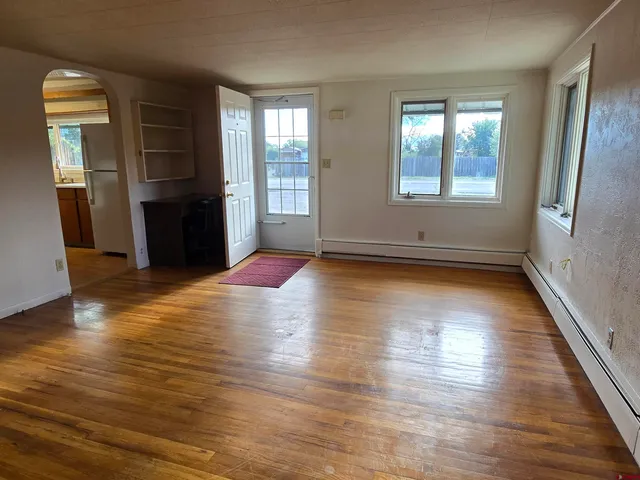 an empty room with wooden floor and windows