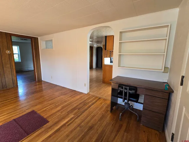 a hallway with wooden floor table and chairs