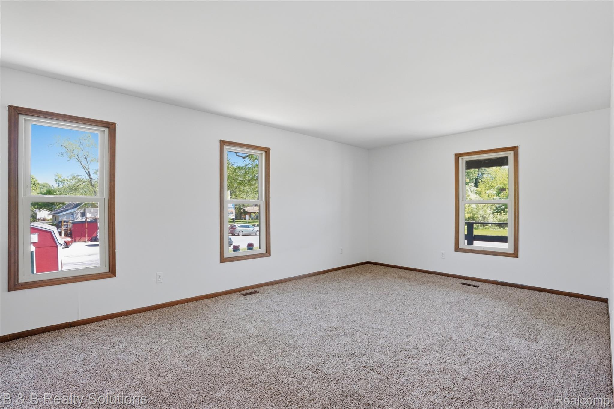 780 North Van Dyke Road, Unit APARTMENT #1 Almont, MI 48003 - Photo 17 of 28 Spacious room featuring three windows with wood-finish trim, white walls, and neutral-toned carpeting