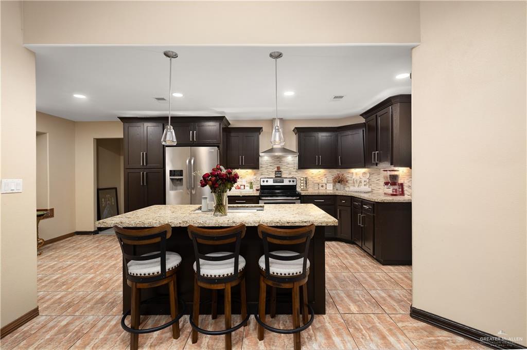 704 Goodwin Acres Road Mission, TX 78574 - Photo 7 of 26 a kitchen with stainless steel appliances a dining table chairs refrigerator and microwave