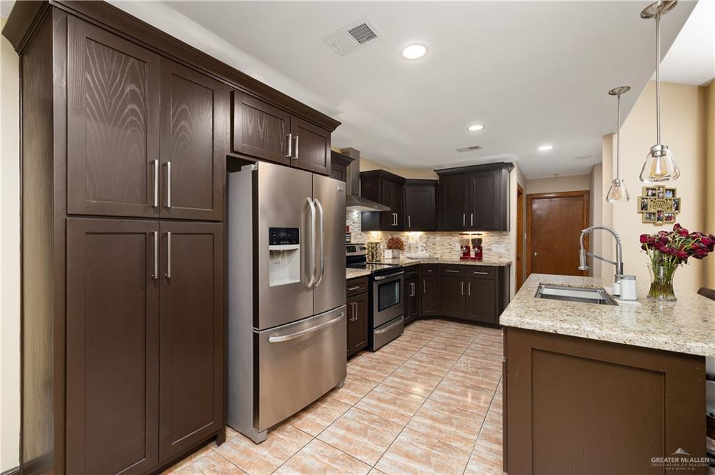 704 Goodwin Acres Road Mission, TX 78574 - Photo 8 of 26 a kitchen with a refrigerator a sink and cabinets