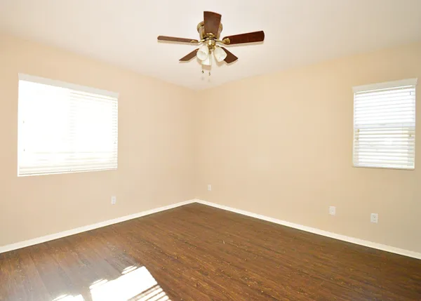 an empty room with wooden floor and windows