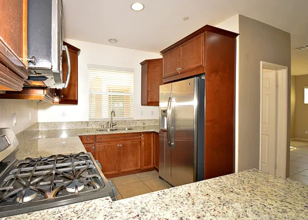 a kitchen with stainless steel appliances granite countertop a stove a refrigerator and a sink