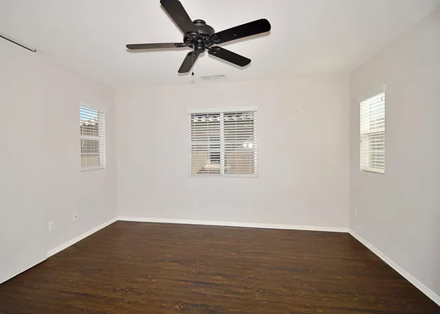 a view of empty room with wooden floor and fan